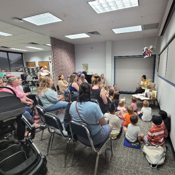 Library staff reading a picture book to a room of children and parents