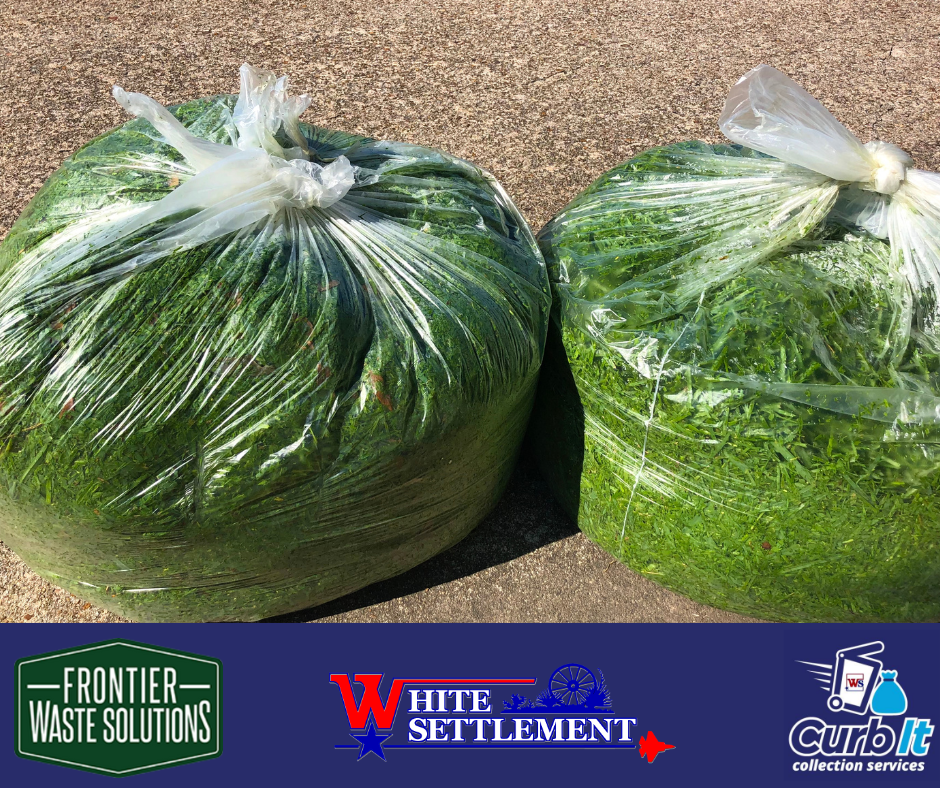 two clear garbage bags full of grass trimmings sitting on the ground